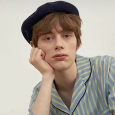 a young man wearing a blue hat and striped shirt