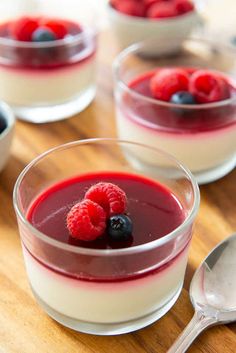 three desserts with berries and yogurt in small bowls on a wooden table