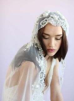 a woman wearing a veil and holding her hands to her face while she is looking down