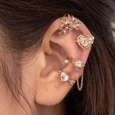 a woman wearing three different ear piercings with flowers and hearts on the back of her ear