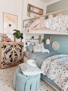 a bedroom with two bunk beds and an ottoman in front of the bed is filled with pillows