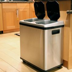 a silver trash can sitting on top of a wooden floor next to a kitchen counter