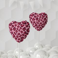 two heart shaped lollipops sitting on top of each other in front of white balls