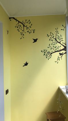 the wall is painted with birds and tree branches