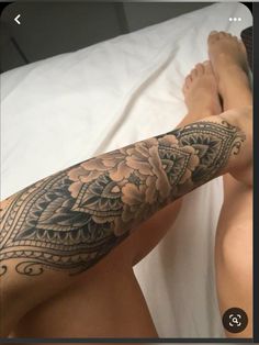 a man with a tattoo on his arm and leg is laying in bed next to another person