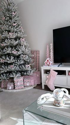 a living room with a christmas tree and presents in front of the tv on a stand