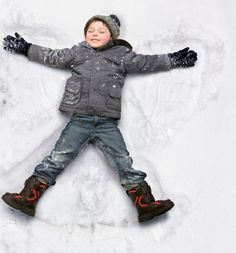 a young boy laying in the snow with his arms outstretched