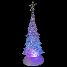 a lighted christmas tree on top of a white base with purple and blue lights around it