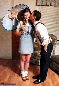 a man kissing a woman with an umbrella in front of her on a wooden floor