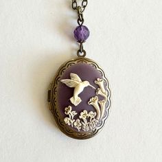 "Here is a sweet hummingbird locket necklace featuring a purple cameo with a hummingbird and calla lily flowers. This vintage inspired locket is antiqued brass with nice detailing. It comes with one faceted amethyst bead at the top along with a nice quality soldered brass chain and a solid brass clasp. Handcrafted by Botanical Bird jewelry in the USA, all materials are lead and nickel safe. Perfect for gift giving, this necklace is shipped in a lovely gift box! The cameo is resin, the locket is Purple Hummingbird, Necklace Sister, Bff Necklace, Calla Lily Flowers, Rectangle Necklace, Victorian Locket, Preppy Beach, Holiday Necklace, Lily Flowers