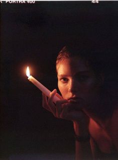 a young man holding a lit candle in his right hand and looking at the camera