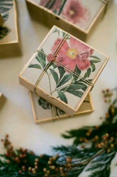 four coasters with flowers on them sitting next to pine branches