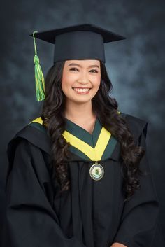 a woman wearing a graduation cap and gown posing for a photo in front of a dark background