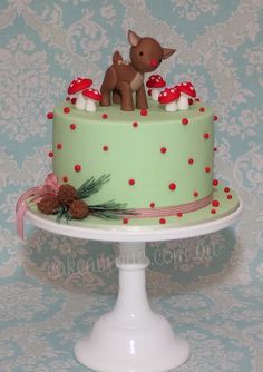 there is a green cake with red dots on it and a deer figurine on top