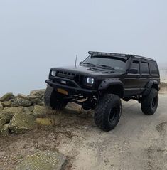 a black truck driving down a dirt road