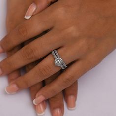 a woman's hand with two diamond rings on her left and the other hand holding an engagement ring