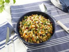 a bowl filled with rice and vegetables on top of a table next to silverware