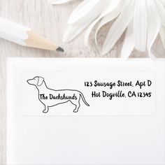 a white envelope with a black dog on it and a pencil next to it that says, the dachshund