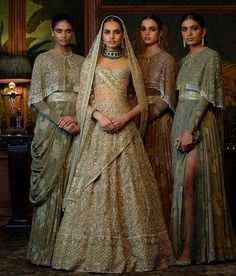 three women standing next to each other in dresses and veils, with one woman wearing a