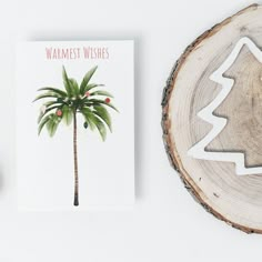 a card with a palm tree on it next to a christmas tree cutout and a wood slice