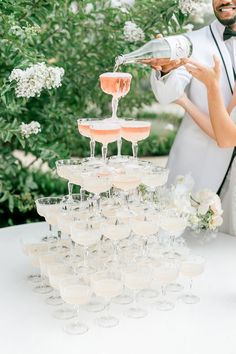 a bride and groom are pouring champagne into wine glasses