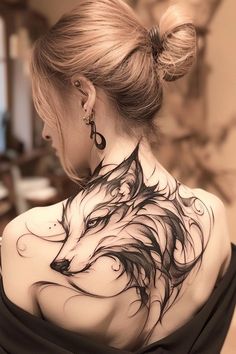 the back of a woman's neck with a wolf tattoo on her upper part