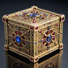 an elaborately designed gold box with blue and red stones on the front, sitting on a reflective surface