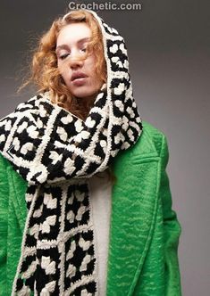 a woman with red hair wearing a green sweater and black and white knitted scarf