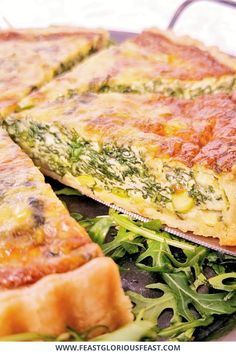 there are two slices of quiche on top of the green leafy salad, and one slice is missing