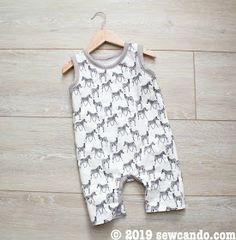 a baby romper with horses on it is laying on the floor next to a wooden hanger