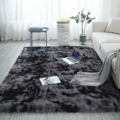 a living room with a couch, table and laptop on the floor in front of a window