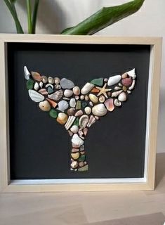 there is a framed picture with shells in the shape of a whale's tail