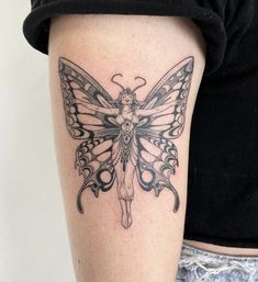 a black and white photo of a butterfly tattoo on the right thigh, with a woman's body in the background