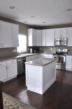 an empty kitchen with white cabinets and stainless steel appliances, wood flooring and hardwood floors