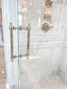 a bathroom with marble walls and flooring, including a glass shower door that has two handles on each side