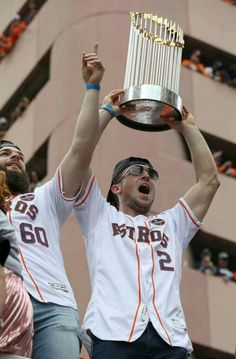 two men holding up a trophy in the air