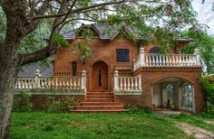 an old brick house with white balconies on the porch and balcony railings