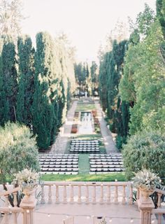 an outdoor ceremony set up with chairs and tables in the foreground, surrounded by trees