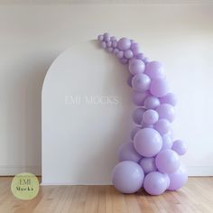 an arch made out of balloons in front of a white wall with the word emi mocks on it