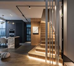 an open living room and dining area with stairs leading up to the top floor is lit by recessed lighting