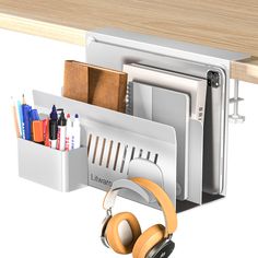 a computer desk with headphones, pens and other office supplies on it's shelf