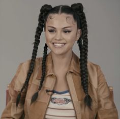 a woman with long braids sitting in a chair and smiling at the camera while wearing a leather jacket