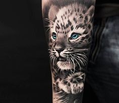 a man's arm with a black and white tattoo of a snow leopard on it