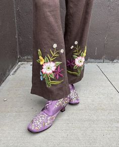 a person wearing purple shoes with flowers painted on the side of their legs and feet