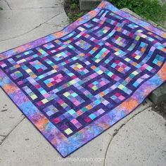 a colorful quilt is laying on the sidewalk