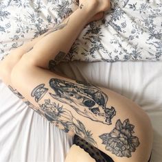 a woman laying on top of a bed next to a comforter covered in tattoos