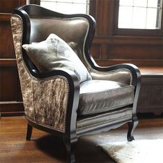 a chair sitting in front of a window on top of a hard wood floor next to a rug