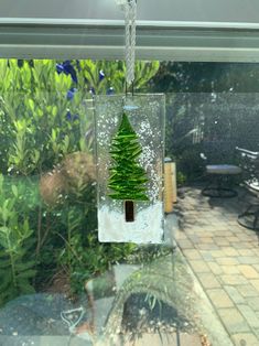 a glass hanging ornament with a tree in it