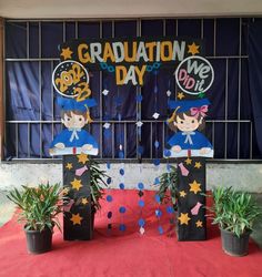 graduation decorations are on display in front of a gated area with potted plants