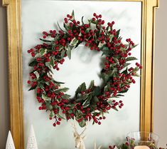 a christmas wreath is hung on the wall above a mantle with candles and other holiday decorations